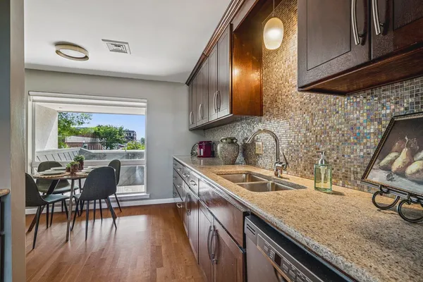 a kitchen with stainless steel appliances granite countertop a sink a stove and a wooden floors