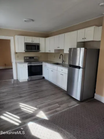 a kitchen with stainless steel appliances a refrigerator stove and white cabinets