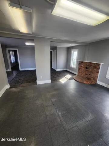 a view of an empty room with window and wooden floor