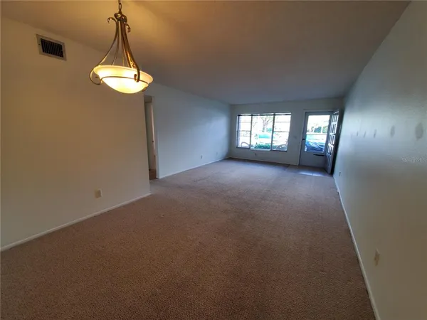 a view of empty room with window and chandelier