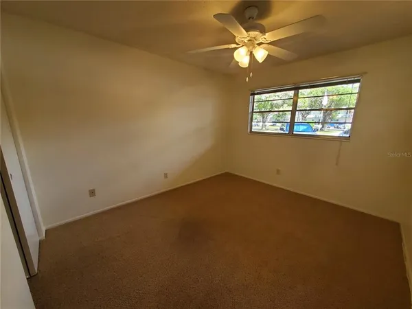 an empty room with windows and fan