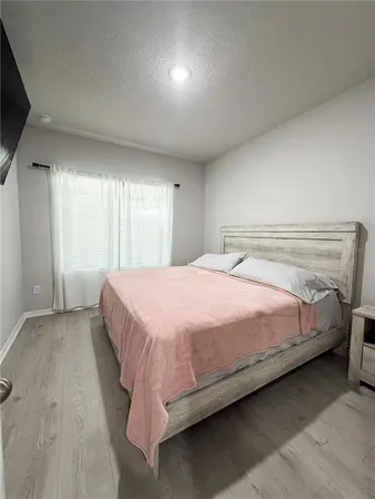 a bedroom with a bed and a flat tv screen on a dresser