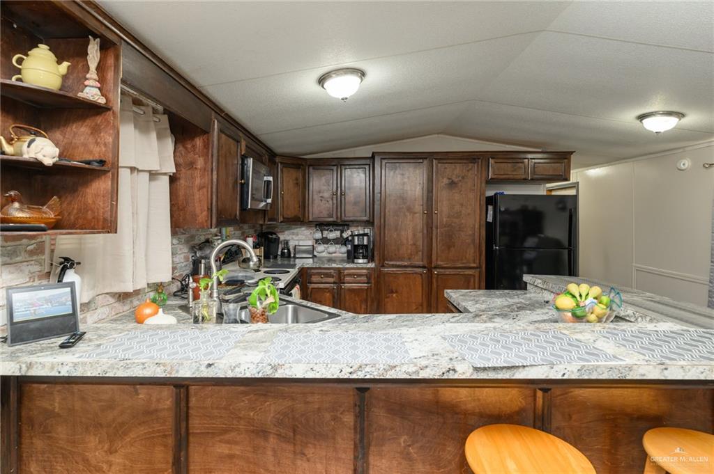 36338 Marshall Hutts Road Rio Hondo, TX 78583 - Photo 7 of 42 a kitchen with granite countertop a sink a stove and wooden cabinets