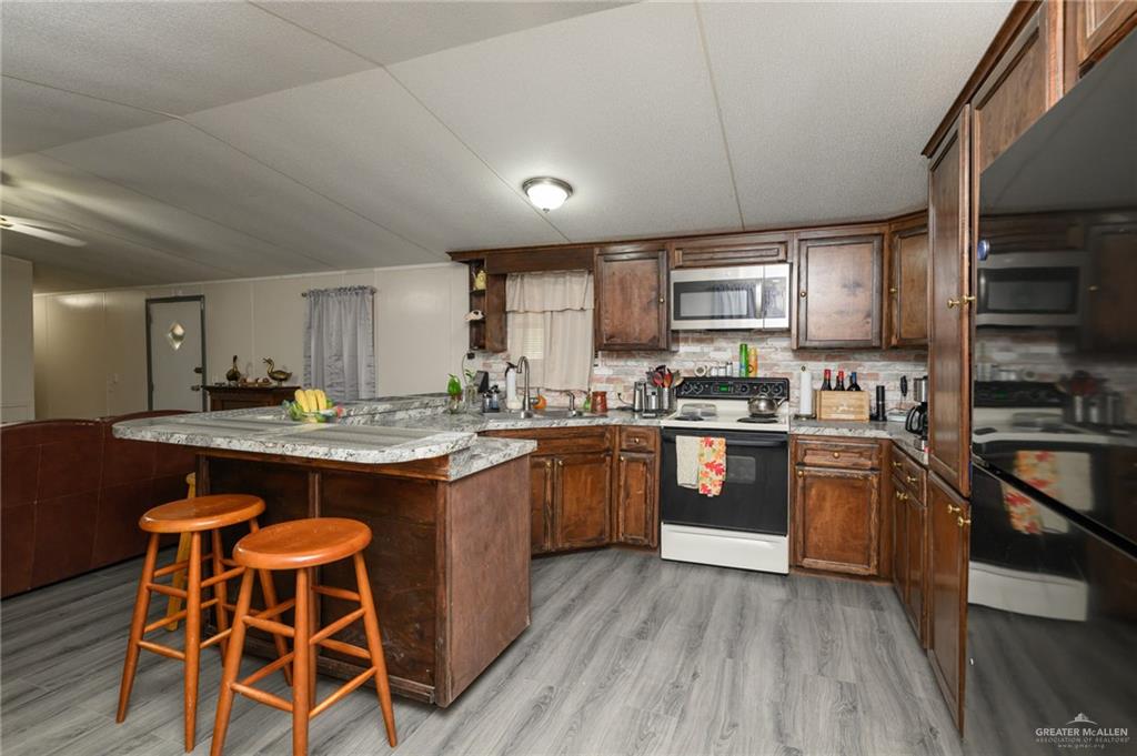 36338 Marshall Hutts Road Rio Hondo, TX 78583 - Photo 8 of 42 a kitchen with stainless steel appliances granite countertop wooden floors stove top oven and refrigerator