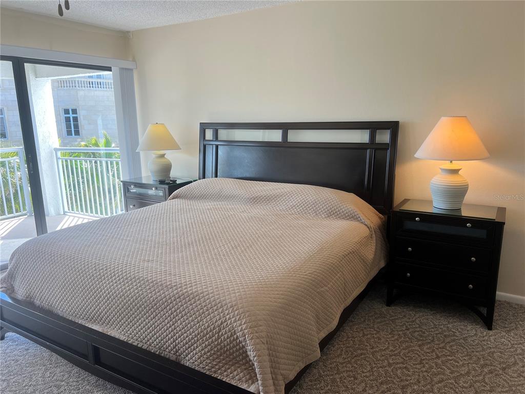 1001 Point Of Rocks Road, Unit 309 Sarasota, FL 34242 - Photo 12 of 38 a bed sitting in a bedroom next to a lamp