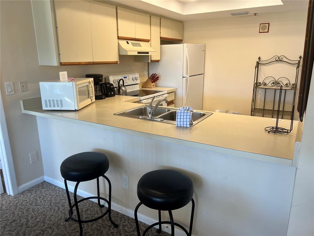 1001 Point Of Rocks Road, Unit 309 Sarasota, FL 34242 - Photo 5 of 38 a kitchen with a table chairs and a refrigerator