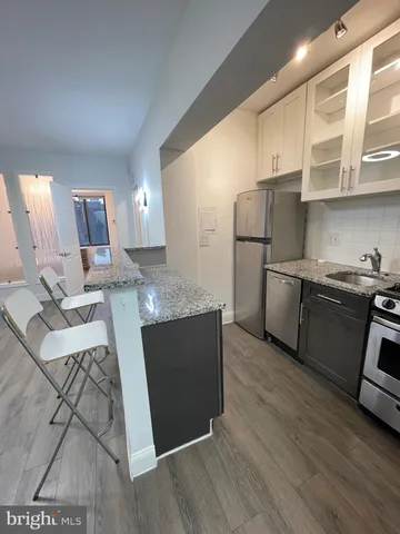 a kitchen with stainless steel appliances granite countertop a refrigerator a sink dishwasher a stove with wooden floors and cabinets