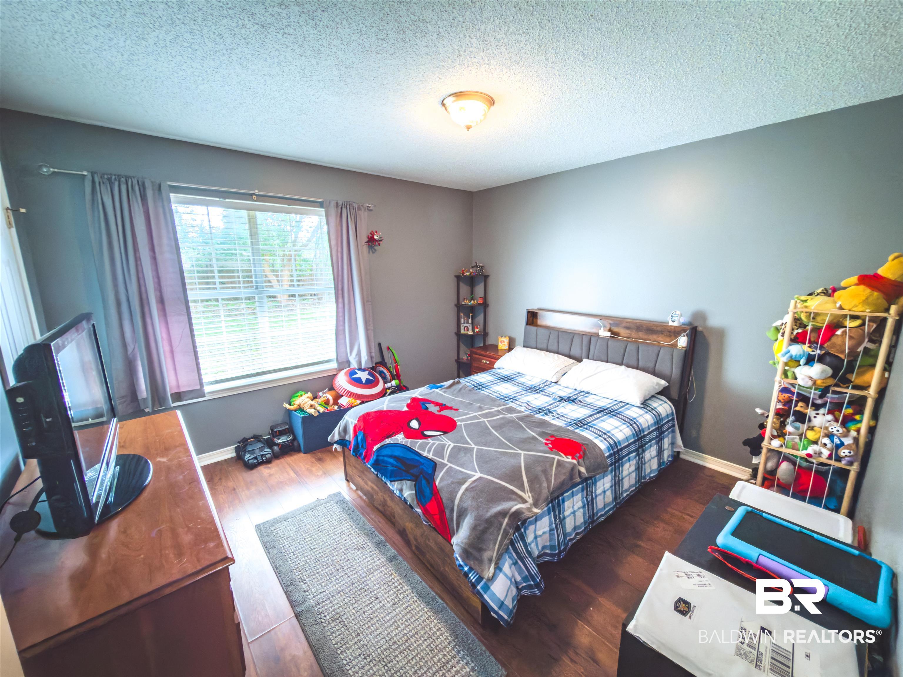 129 Pennbrooke Loop Foley, AL 36535 - Photo 15 of 44 Bedroom featuring dark wood-type flooring and a textured ceiling