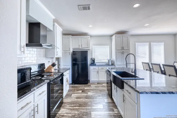 a kitchen with granite countertop a sink stainless steel appliances and cabinets