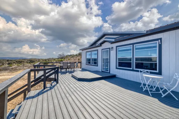 a view of a roof deck with table and chairs a barbeque with wooden floor and fence