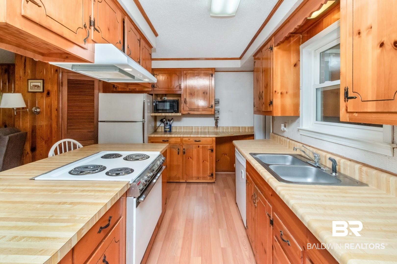6300 Woodcrest Drive Mobile, AL 36608 - Photo 10 of 35 Kitchen with white appliances, light countertops, under cabinet range hood, light wood-style floors, and brown cabinetry
