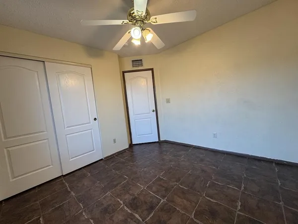 an empty room with windows and fan
