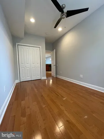 an empty room with wooden floor cabinet and windows