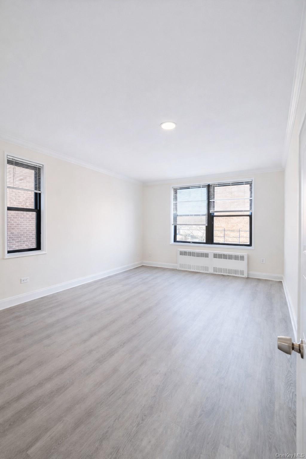 150-11 72nd Road, Unit 4 Queens, NY 11367 - Photo 6 of 12 an empty room with wooden floor and windows