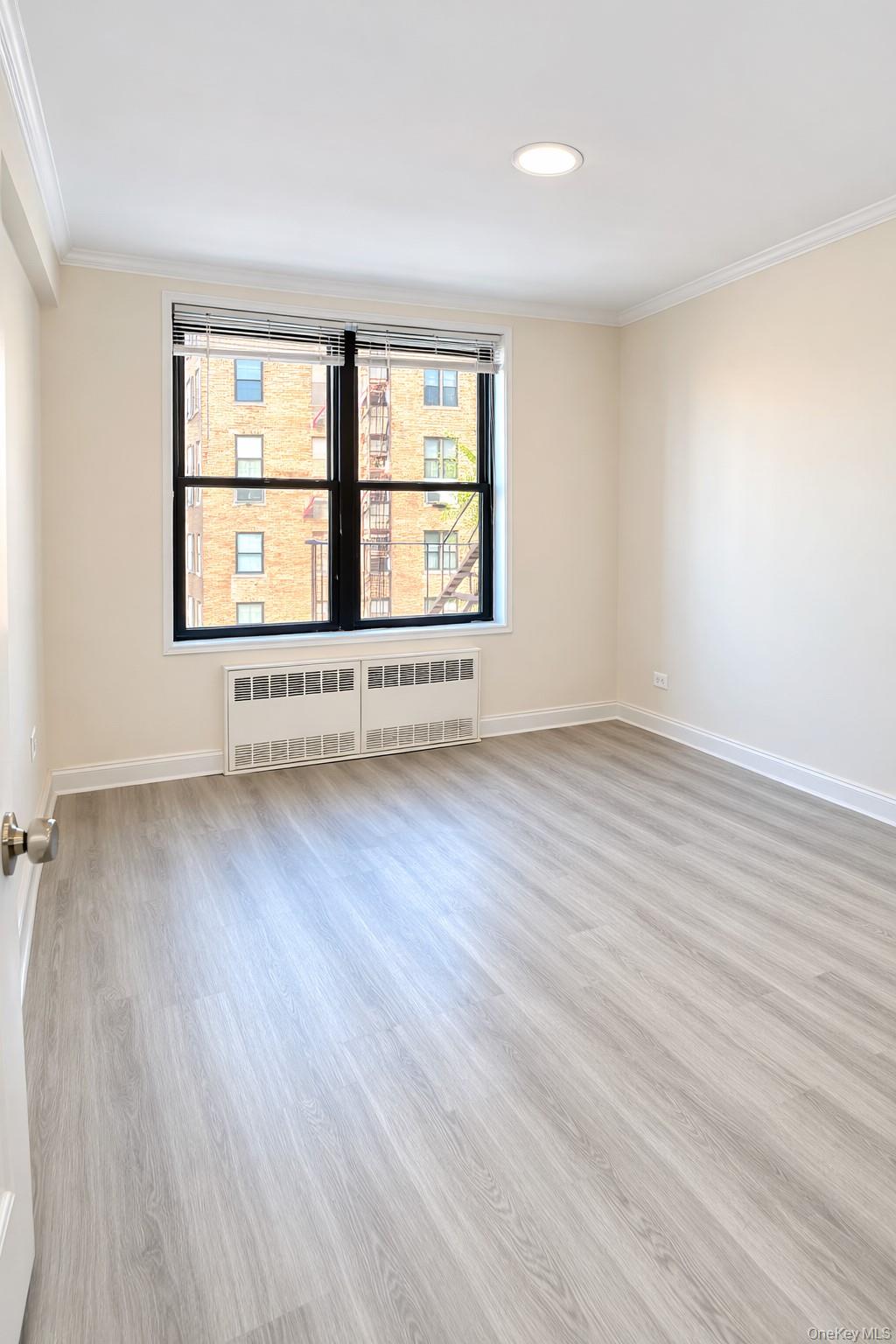 150-11 72nd Road, Unit 4 Queens, NY 11367 - Photo 7 of 12 an empty room with wooden floor and windows