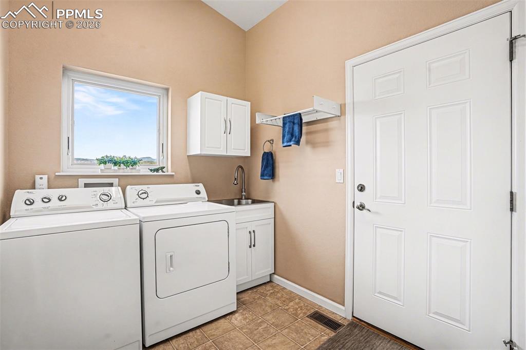 459 Bowie Road Penrose, CO 81240 - Photo 18 of 47 The laundry room is well-appointed and functional, featuring a stainless steel utility sink with cabinet, additional cabinetry, drying rack, and window. It provides direct access to the attached 2-car garage, making chores convenient while keeping the space organized and efficient.