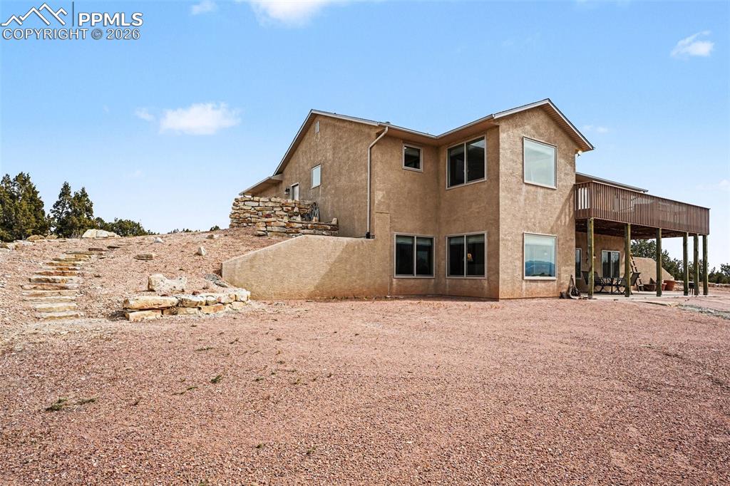 459 Bowie Road Penrose, CO 81240 - Photo 33 of 47 The back of the home features a walk-out basement with access to a concrete patio, providing ample space for outdoor entertaining, dining, or relaxing. This area overlooks the expansive open land and mountain views, seamlessly connecting the interior living spaces with the peaceful Colorado landscape.