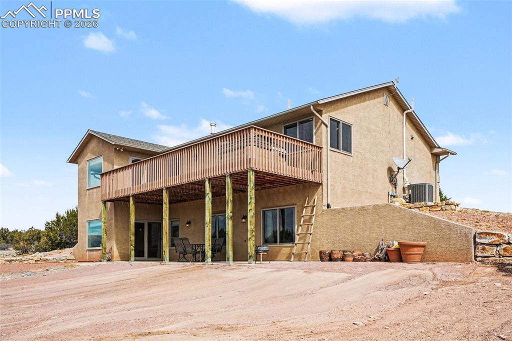 459 Bowie Road Penrose, CO 81240 - Photo 34 of 47 The back of the home features a walk-out basement with access to a concrete patio, providing ample space for outdoor entertaining, dining, or relaxing. This area overlooks the expansive open land and mountain views, seamlessly connecting the interior living spaces with the peaceful Colorado landscape.