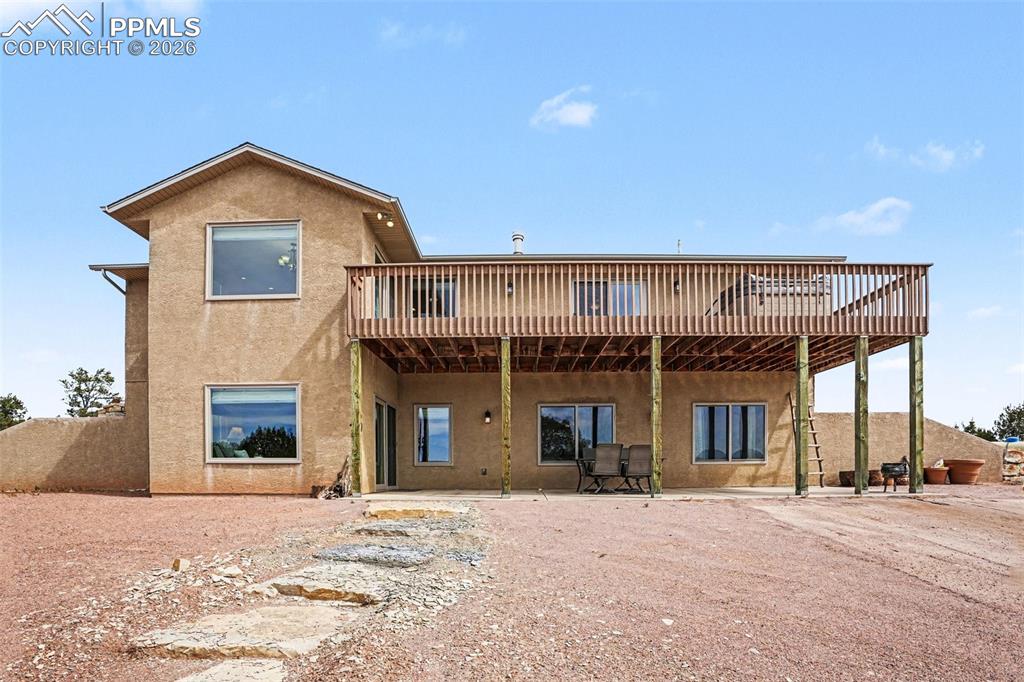 459 Bowie Road Penrose, CO 81240 - Photo 35 of 47 The back of the home features a walk-out basement with access to a concrete patio, providing ample space for outdoor entertaining, dining, or relaxing. This area overlooks the expansive open land and mountain views, seamlessly connecting the interior living spaces with the peaceful Colorado landscape.