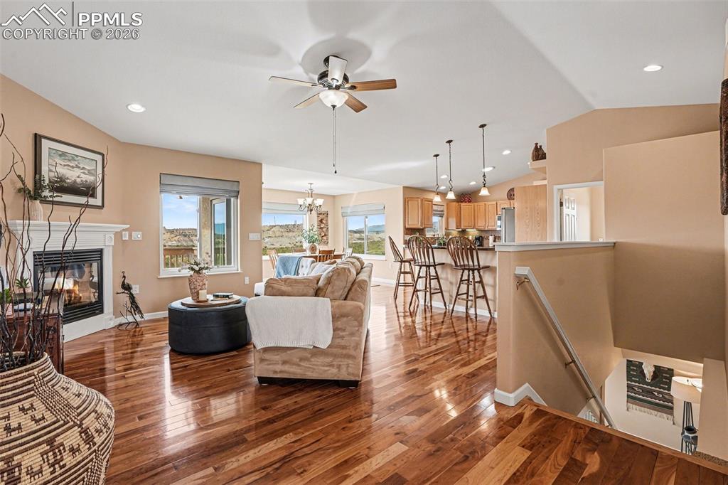 459 Bowie Road Penrose, CO 81240 - Photo 9 of 47 The living room features vaulted ceilings and beautiful cherry hardwood flooring, creating an open and inviting space. A cozy gas fireplace serves as the focal point, perfect for relaxing or entertaining.