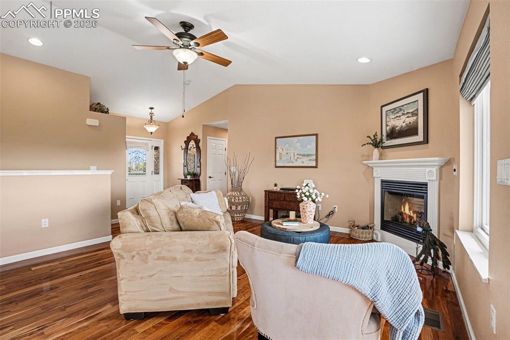 459 Bowie Road Penrose, CO 81240 - Photo 10 of 47 The living room features vaulted ceilings and beautiful cherry hardwood flooring, creating an open and inviting space. A cozy gas fireplace serves as the focal point, perfect for relaxing or entertaining.