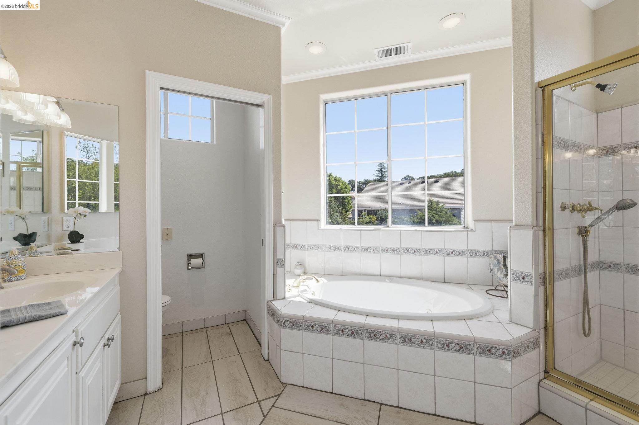 6242 Bluff View Road Copperopolis, CA 95228 - Photo 36 of 59 Bathroom featuring a built-in soaking tub with decorative tile surround, a glass-enclosed shower with gold-tone fixtures, and a vanity with dual sinks