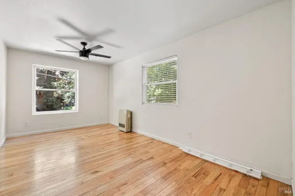 a view of an empty room with a window and wooden floor