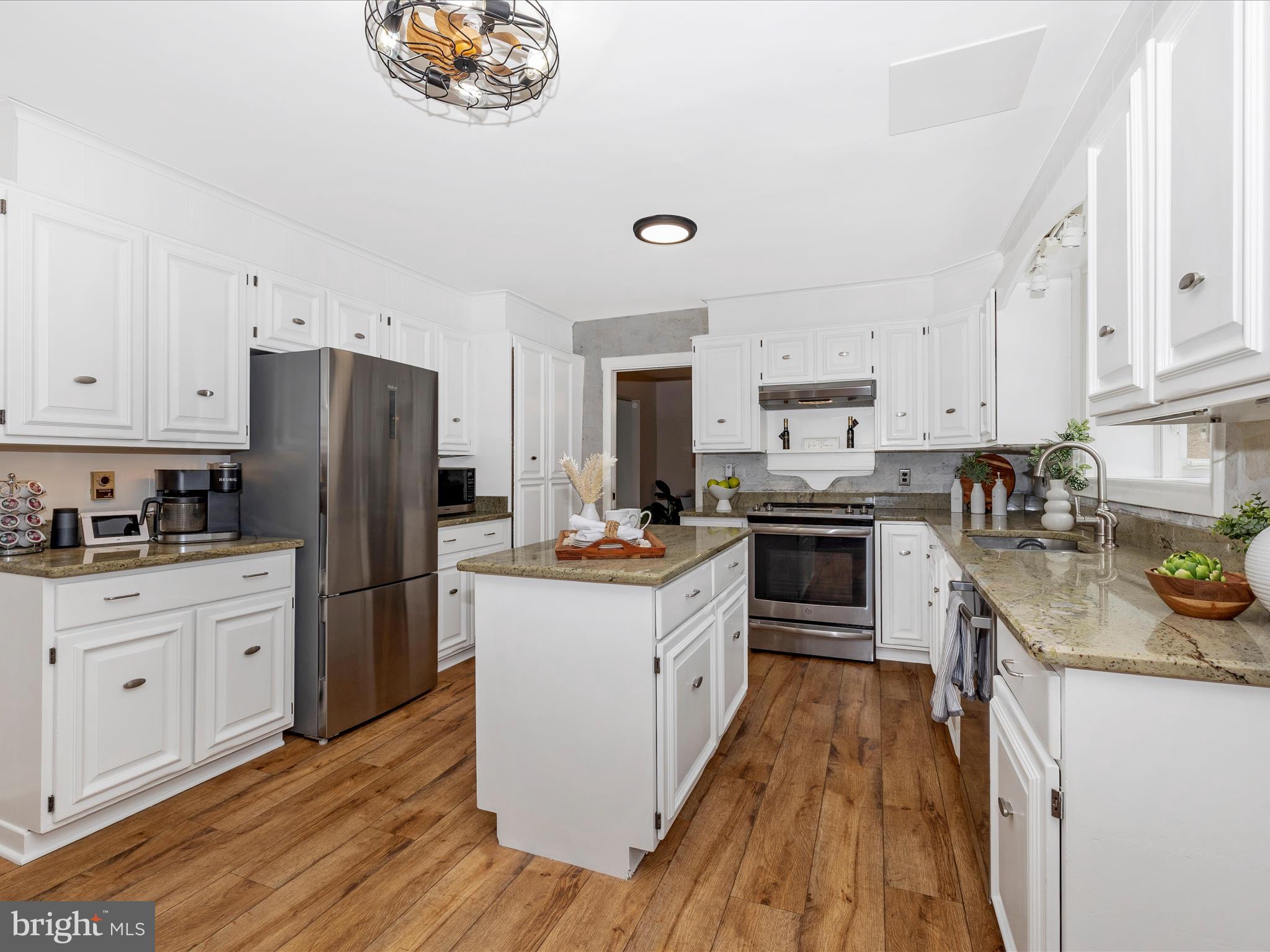 4426 Teen Barnes Road Frederick, MD 21703 - Photo 18 of 76 a kitchen with granite countertop a refrigerator a stove top oven a sink dishwasher and white cabinets with wooden floor