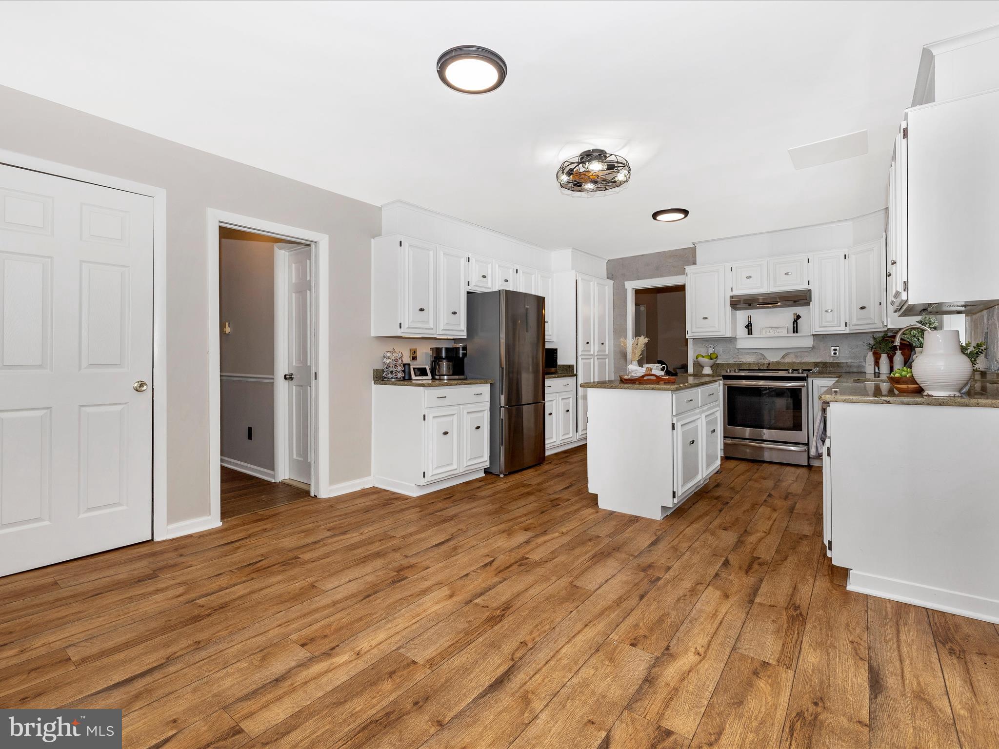 4426 Teen Barnes Road Frederick, MD 21703 - Photo 22 of 76 a kitchen with stainless steel appliances granite countertop a stove top oven a sink dishwasher and a refrigerator with wooden floor