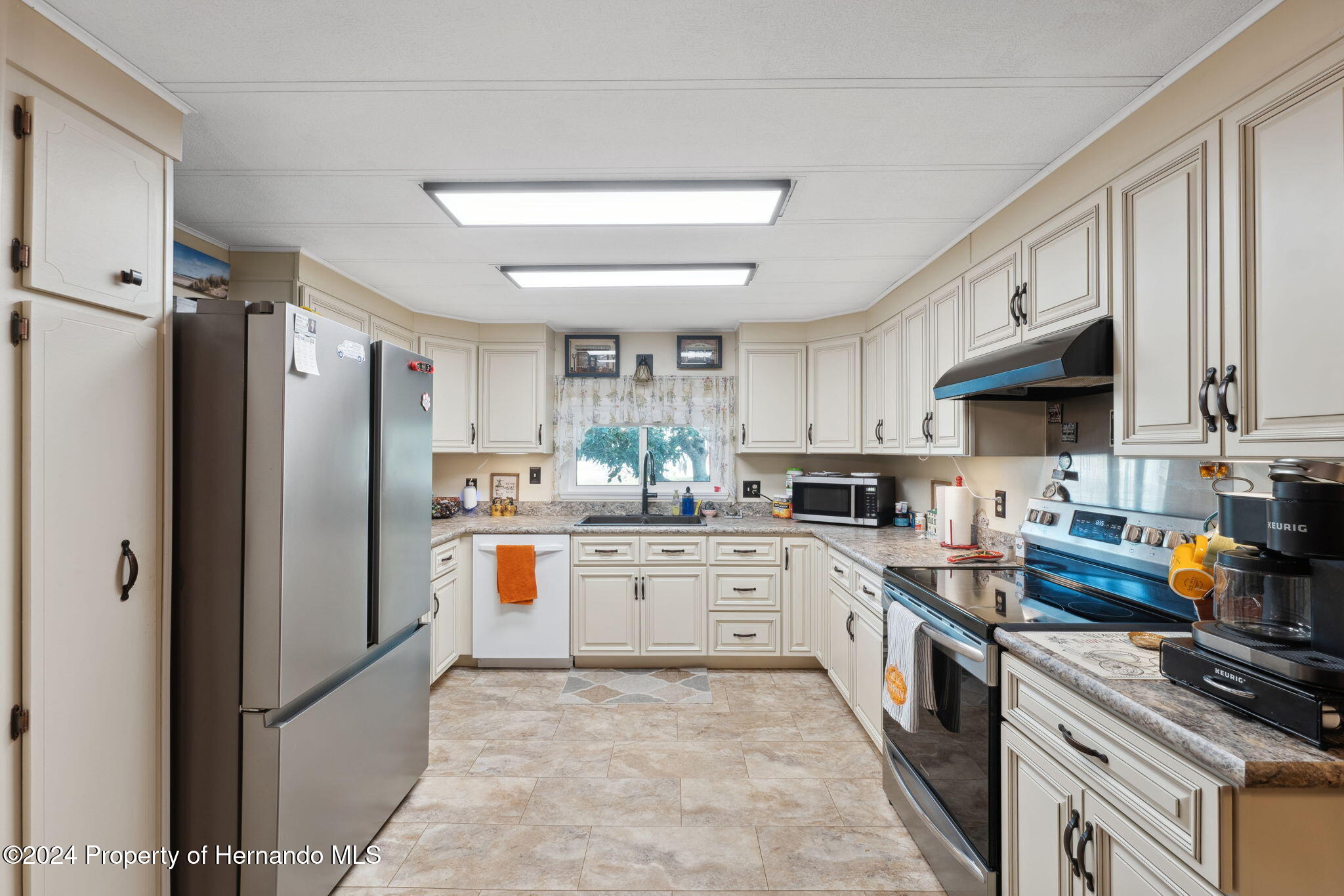 15116 Rialto Avenue Brooksville, FL 34613 - Photo 18 of 36 a kitchen with stainless steel appliances a stove refrigerator sink and microwave