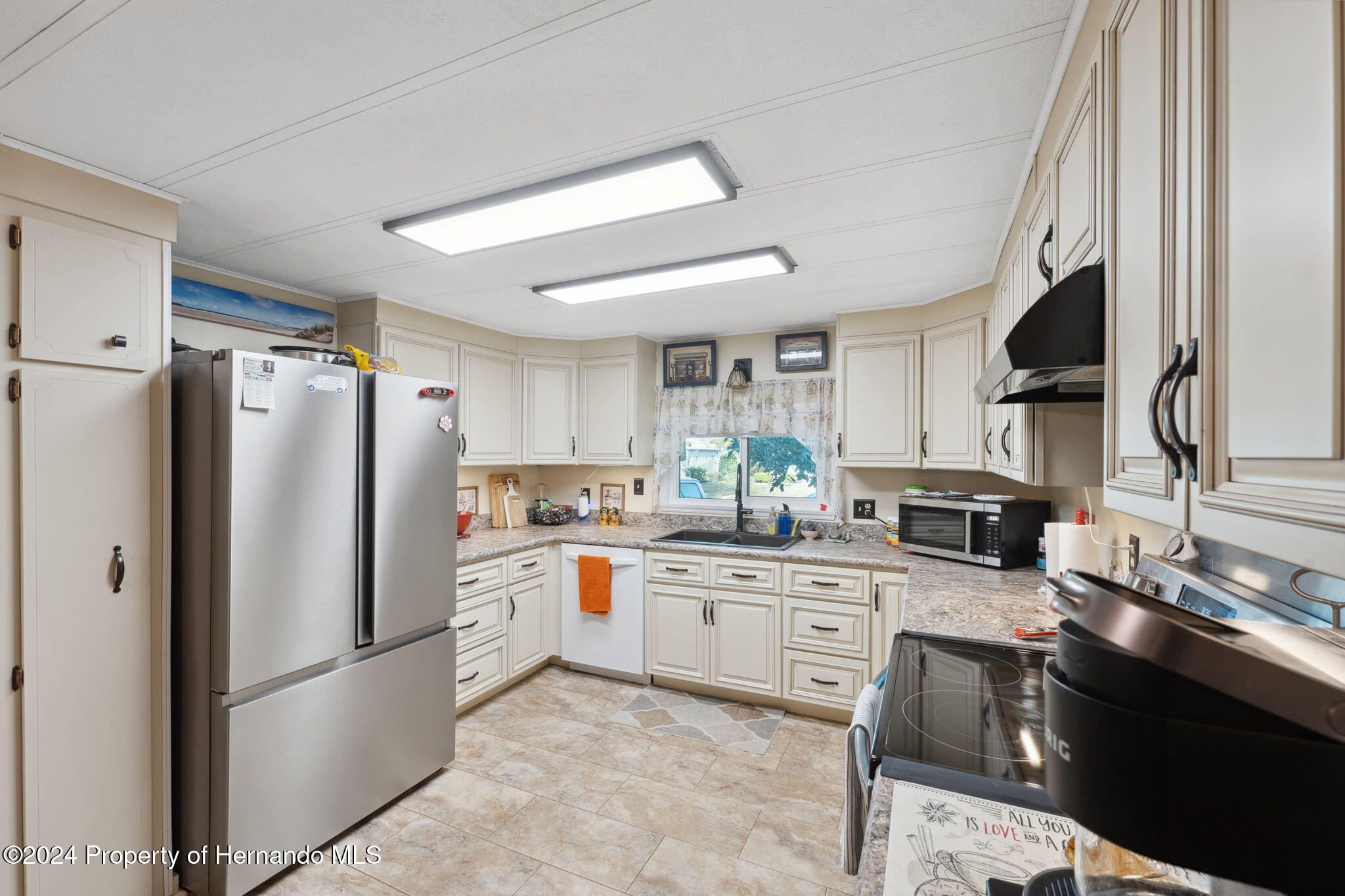 15116 Rialto Avenue Brooksville, FL 34613 - Photo 20 of 36 a kitchen with stainless steel appliances granite countertop a refrigerator a stove a sink and white cabinets with wooden floor