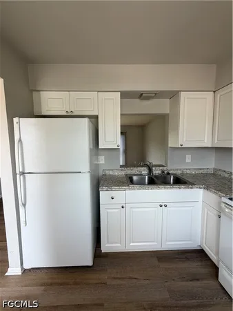 a kitchen with stainless steel appliances a refrigerator a sink and white cabinets