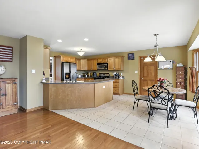 a kitchen with stainless steel appliances kitchen island granite countertop a refrigerator a stove a sink dishwasher and white cabinets with wooden floor