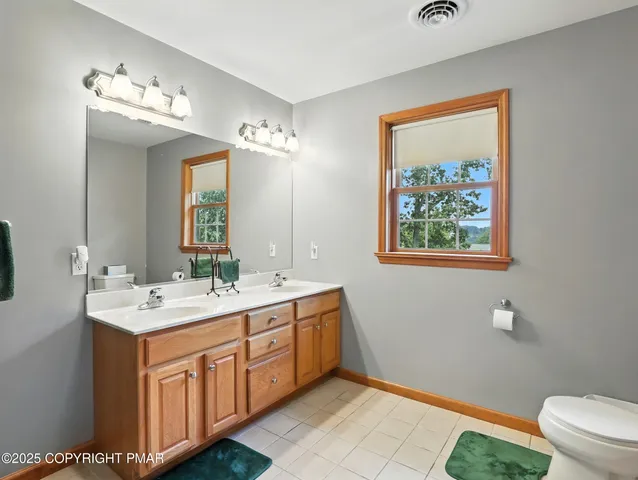 a spacious bathroom with a double vanity sink toilet and a mirror