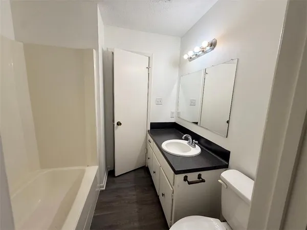 a bathroom with a granite countertop sink a toilet and bathtub