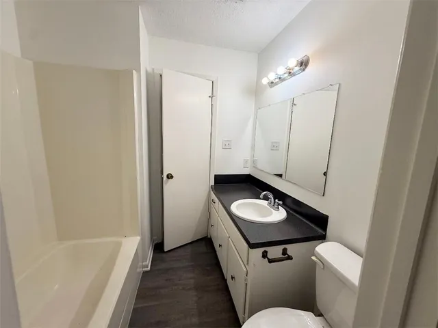 a bathroom with a granite countertop sink a toilet and bathtub
