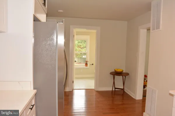 a view of a hallway with wooden floor and a bathroom