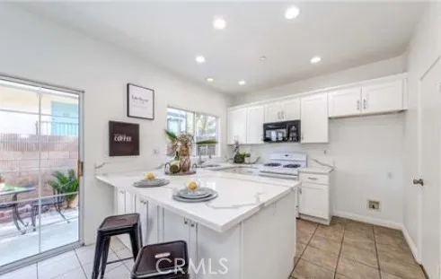 a kitchen with a sink a stove a refrigerator and white cabinets with wooden floor