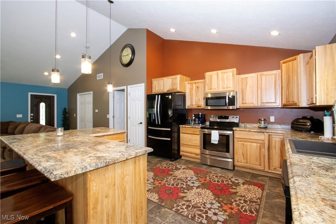 8249 Town Line Road Shiloh, OH 44878 - Photo 33 of 34 Kitchen featuring appliances with stainless steel finishes, high vaulted ceiling, light brown cabinetry, open floor plan, and a kitchen breakfast bar
