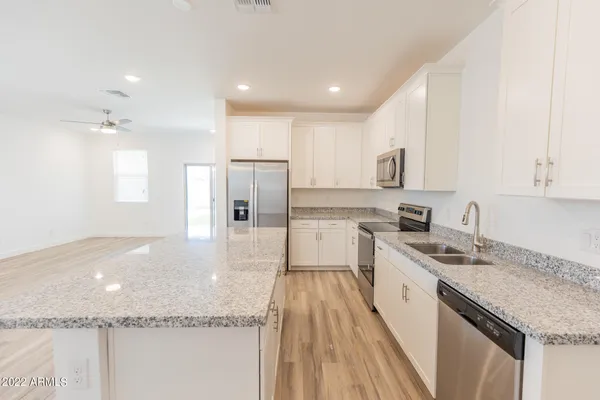 a large kitchen with stainless steel appliances granite countertop a lot of counter space and wooden floors