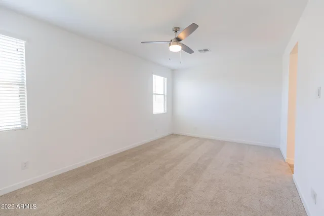an empty room with windows and fan