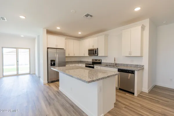 a kitchen with a refrigerator a sink and wooden floor