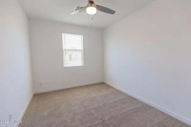 an empty room with a window and a fan