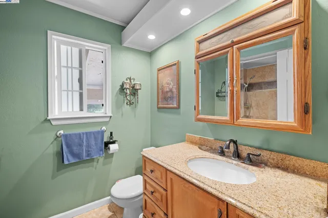 a bathroom with a granite countertop toilet a sink and a mirror