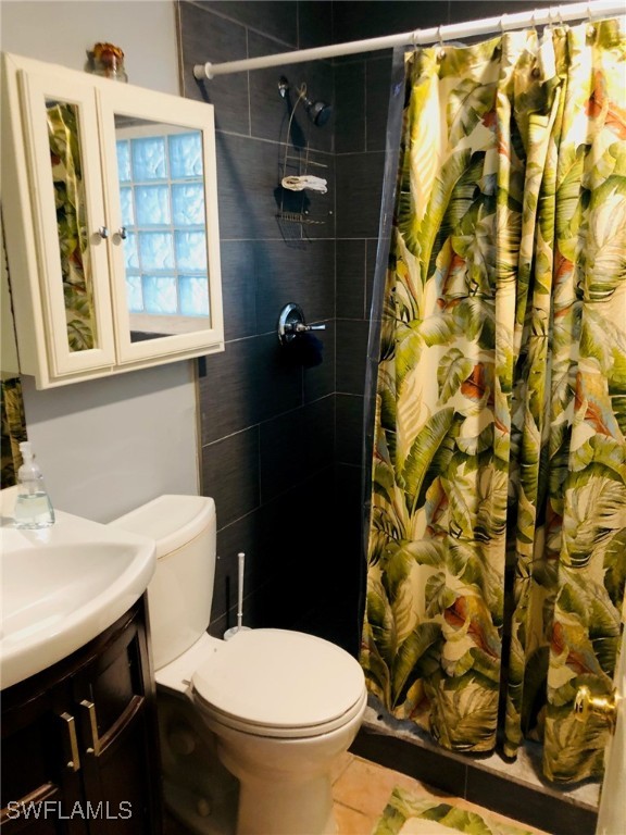 1836 Collier Avenue Fort Myers, FL 33901 - Photo 12 of 19 a white toilet sitting next to a bathroom sink and a shower curtain
