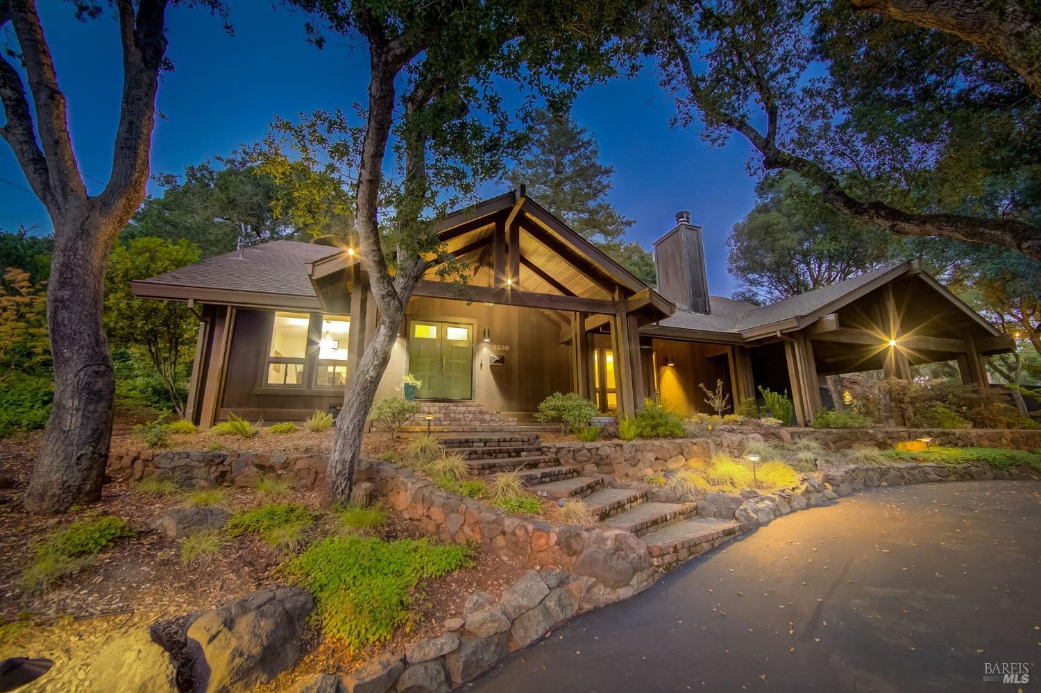 a view of a brick house with large trees