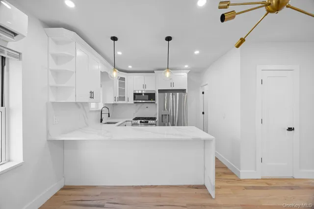 a large white kitchen with kitchen island a sink stainless steel appliances and cabinets