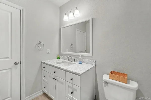 a bathroom with a granite countertop toilet sink and mirror