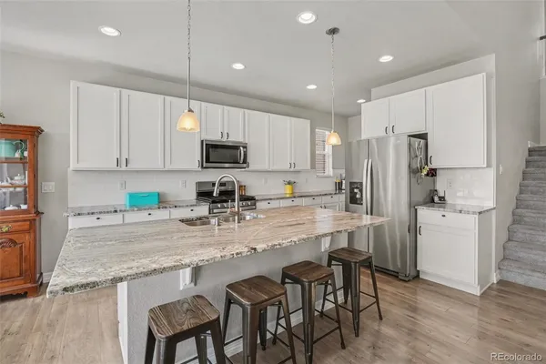 a kitchen with kitchen island granite countertop a refrigerator stove microwave and cabinets