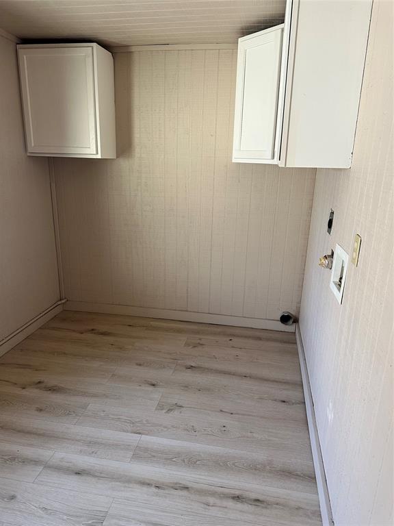 2590 Rock Ridge Road Lucas, TX 75002 - Photo 24 of 25 Utility room featuring wood-finish flooring, light-colored wall paneling, and two wall-mounted white cabinetry units
